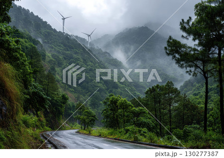 Wind turbines along a winding mountain road in misty morning 130277387