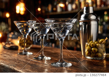 Elegant martini glasses on a polished bar with shaker and olives 130277464