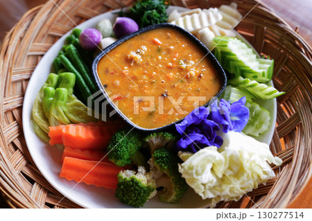 A hand is dipping Chili paste with fresh vegetables, asain cuisine A hand is dipping Chili paste with fresh vegetables, asain cuisine 130277514