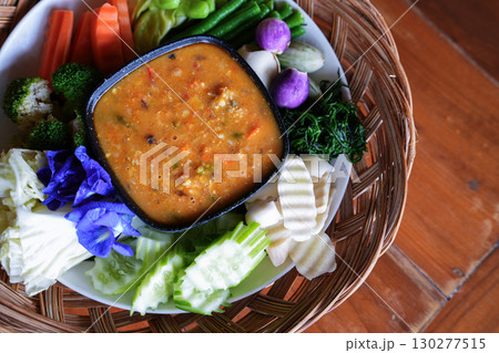A hand is dipping Chili paste with fresh vegetables, asain cuisine 130277515
