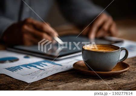 Hands analyzing stock market data with coffee nearby 130277614