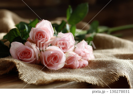 Freshly cut pink roses on rustic burlap in soft light 130278031