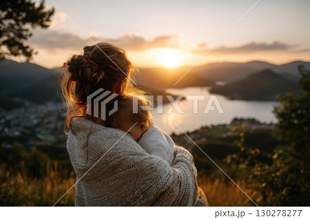 Mother embraces baby while watching sunset at scenic overlook 130278277