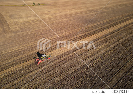 Tractor working on agricultural field, plowed farmland 130278335