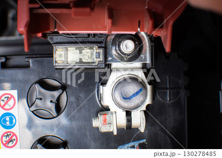 Close-up of a car battery positive terminal in red with fuse and connector 130278485