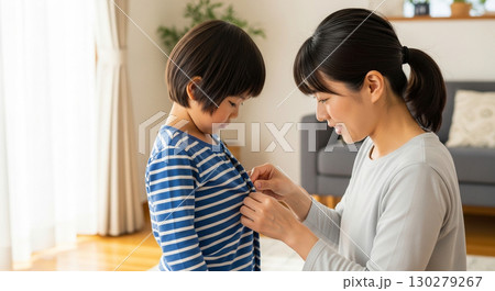 子供の洋服のボタンを掛けてあげているお母さん 130279267