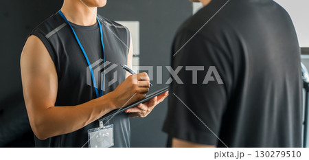 パーソナルジムで会員に個別指導するトレーナーの男性 130279510