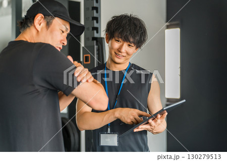 パーソナルジムで会員に個別指導するトレーナーの男性 パーソナルジムで会員に個別指導するトレーナーの男性 130279513