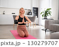 Middle aged blonde woman standing on yoga mat in namaste pose at home, focusing on breathing, mindfulness, and balanced posture 130279707