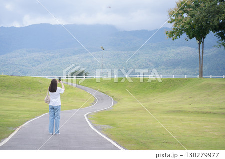 Relax and wellness concept with woman walk on road in garden and mountain background at chiangmai thailand in raining season 130279977