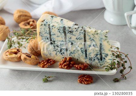 Gorgonzola cheese with walnuts, and thyme on a white table. 130280035