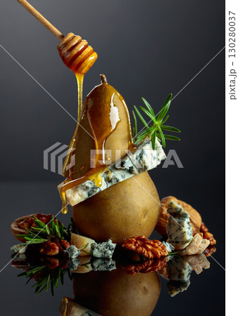 Blue cheese with honey, pear, walnuts, and rosemary on a black background. 130280037