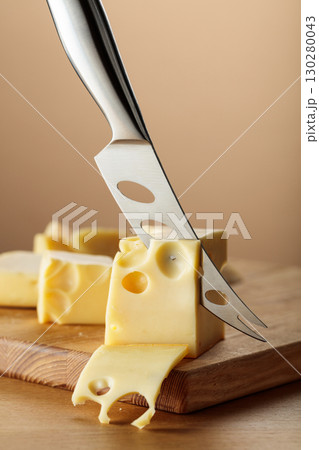 Cheese and knife on a wooden cutting board. Cheese and knife on a wooden cutting board. 130280043