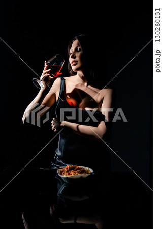 Woman enjoying spaghetti and wine in a studio setting during a photo shoot Woman enjoying spaghetti and wine in a studio setting during a photo shoot 130280131
