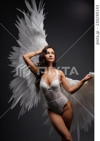 Woman poses gracefully with wings illuminated by soft projective lighting 130280143