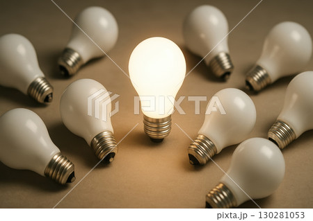 Light bulb glowing among unlit bulbs on brown surface symbolizing innovation and leadership concept 130281053
