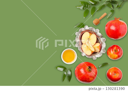 Fresh apples and pomegranates are artfully arranged beside honey 130281390