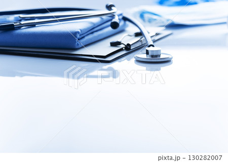 Healthcare medical background with copy-space of stethoscope clipboard and folded overalls on table 130282007