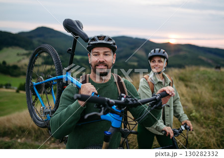 Couple cycling together in nature, smiling and enjoying outdoor adventure. Couple cycling together in nature, smiling and enjoying outdoor adventure. 130282332