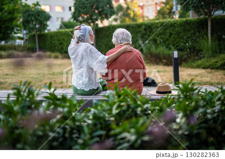 Elderly mother sitting on bench with adult daughter. 130282363