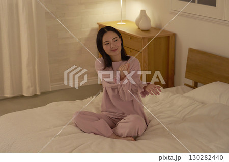 ベッドの上で腕をストレッチする女性 130282440