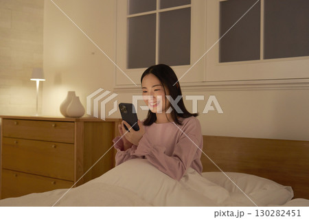 ベッドでスマホを使う女性 130282451