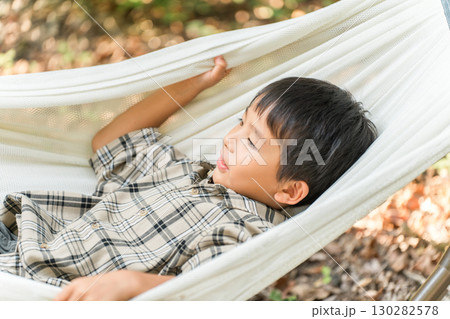 キャンプ場のハンモックで遊ぶ子供・小学生・男の子(アウトドア・旅行・レジャー・ピクニック) キャンプ場のハンモックで遊ぶ子供・小学生・男の子(アウトドア・旅行・レジャー・ピクニック) 130282578