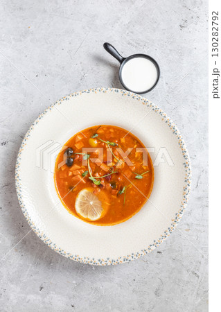 Rich soup with smoked meats, sausages, lemon, and olives, viewed from above on a gray background Rich soup with smoked meats, sausages, lemon, and olives, viewed from above on a gray background 130282792