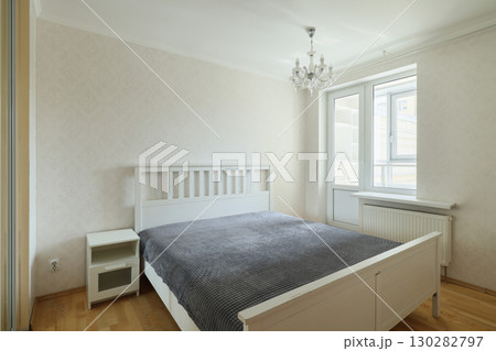A Cozy Modern Bedroom Featuring an Elegant Chandelier and Beautiful Neutral Decor Elements 130282797