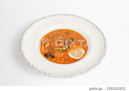 Rich soup with smoked meats, sausages, lemon, and olives on a white background Rich soup with smoked meats, sausages, lemon, and olives on a white background 130282832