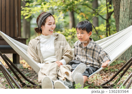 キャンプ場のハンモックで遊ぶ家族・ファミリー（アウトドア・旅行・レジャー・ピクニック） 130283564
