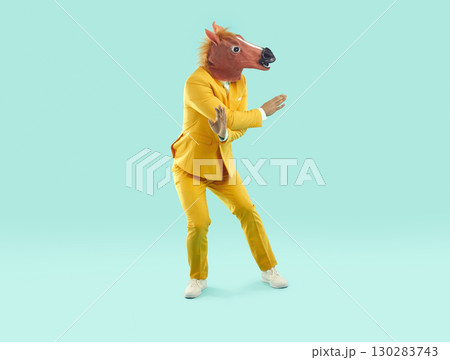 Full length shot of dancing young man in horse head mask Full length shot of dancing young man in horse head mask 130283743