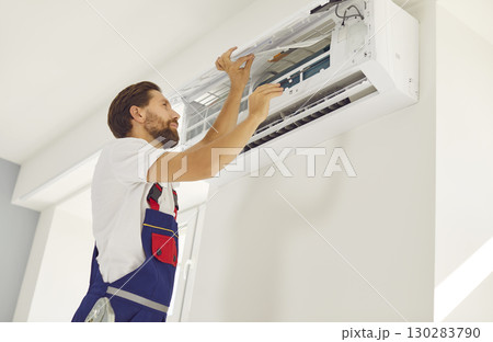 Air conditioning installation, repair and maintenance service worker fixes something in AC 130283790