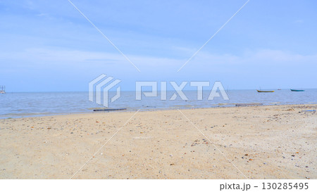 Sandy Beach with Calm Sea and Traditional Fishing Boats under Blue Sky 130285495