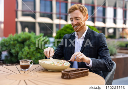 Red-haired businessman enjoying lunch at outdoor cafe table Red-haired businessman enjoying lunch at outdoor cafe table 130285568