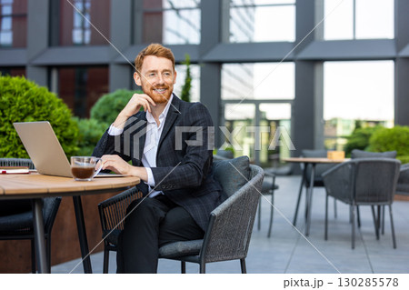 Bearded redhead using laptop at outdoor table in business district 130285578