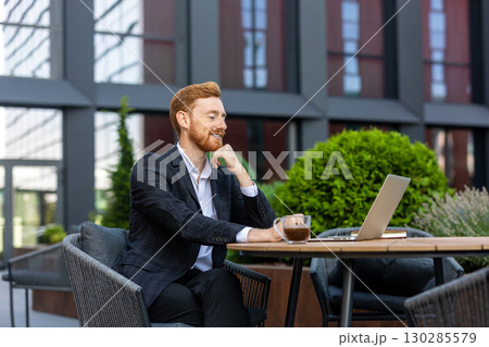 Red-haired businessman having video call on laptop at cafe Red-haired businessman having video call on laptop at cafe 130285579