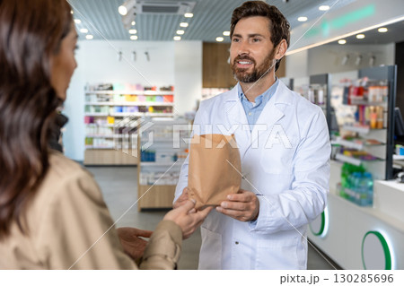 Dark-haired pretty young woman talking to the pharmacist and looking interested Dark-haired pretty young woman talking to the pharmacist and looking interested 130285696
