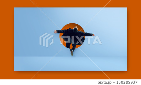 Digital artwork. Businessman jumping through round doorway on blue wall with open arms and dramatic fashion expression 130285937