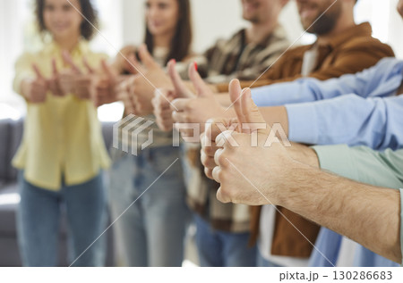 Several happy young men and women recommend something and give thumbs up together Several happy young men and women recommend something and give thumbs up together 130286683