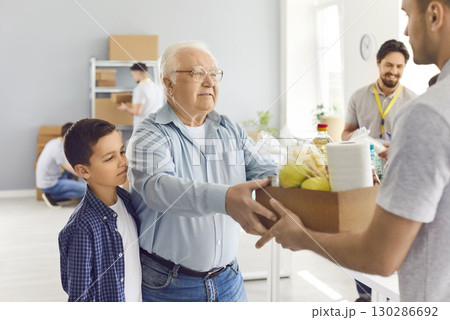 Elderly man and child receive a box of food from a volunteer, close-up Elderly man and child receive a box of food from a volunteer, close-up 130286692