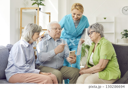 Senior group with supporting caring kind female medical nurse helping senior patient with phone call Senior group with supporting caring kind female medical nurse helping senior patient with phone call 130286694