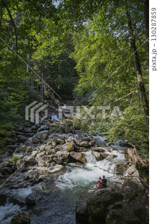 Couple seated by a cascading stream in the Pyrenees at Cauterets by Pont d'Espagne among the lush Couple seated by a cascading stream in the Pyrenees at Cauterets by Pont d'Espagne among the lush 130287859
