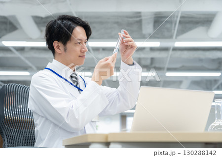 研究所で実験をする白衣の若い男性研究者 130288142