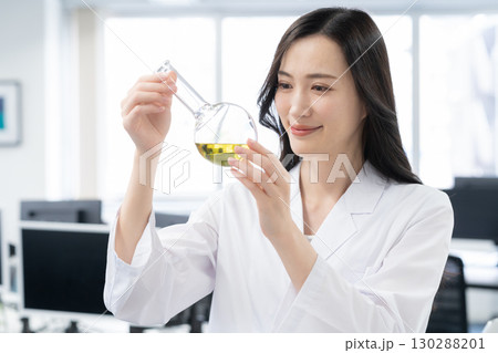 研究所で実験をする白衣の若い女性研究者 130288201