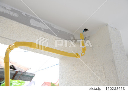 Close up detail of yellow gas pipe during house renovation. construction scene shows new installation on white wall. unfinished state gives feeling of progress Close up detail of yellow gas pipe during house renovation. construction scene shows new installation on white wall. unfinished state gives feeling of progress 130288638