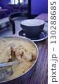 Korean fried chicken covered in melted cheese served in a metal bowl with a cup of hot drink in the background. The image captures indulgence, comfort food and urban dining culture 130288685