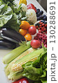 A colorful variety of fresh fruits and vegetables including corn, berries, tomatoes, eggplants and greens arranged on a white surface 130288691