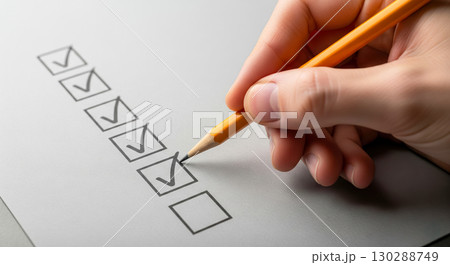 Hand holding yellow pencil and putting check mark in checkbox on list, person filling out survey, exam or to-do list concept, business management 130288749