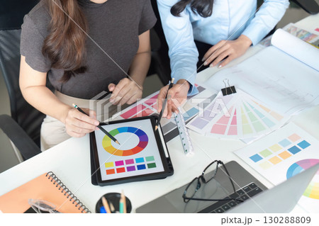 Color Selection. Women architects discussing color schemes and design strategies at a desk. 130288809